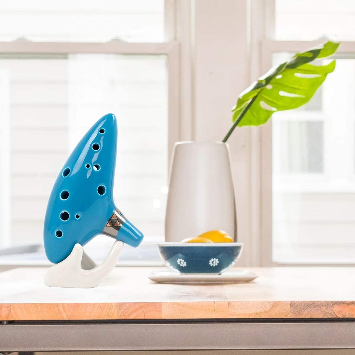 A ceramic Ocarina resting on a counter next to a vase