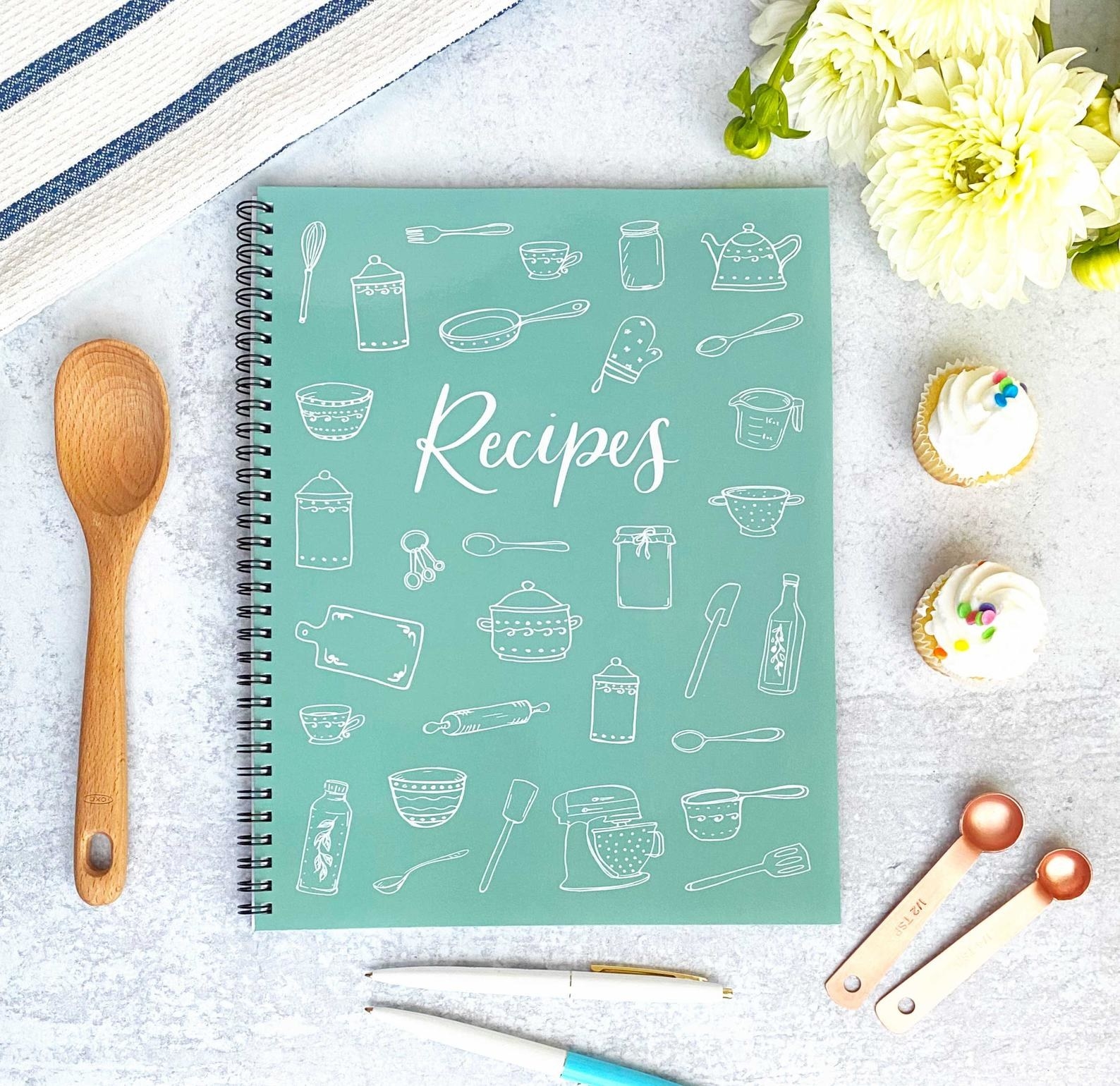 The spiral book in turquoise with illustrations of kitchen items on the cover