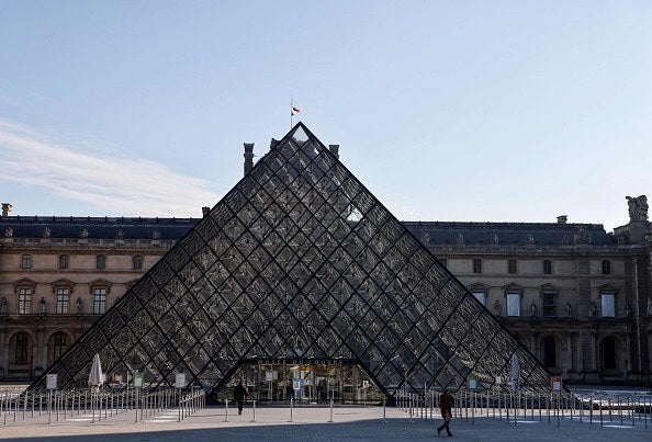A pedestrian walks in front of The Louvre Museum in Paris on November 6, 2020, during a lockdown imposed by authorities in an attempt to halt the spread of the new coronavirus