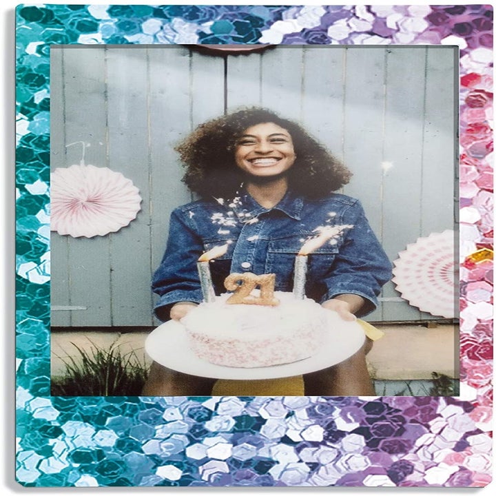 A instant photograph with a glittery border of someone holding a birthday cake