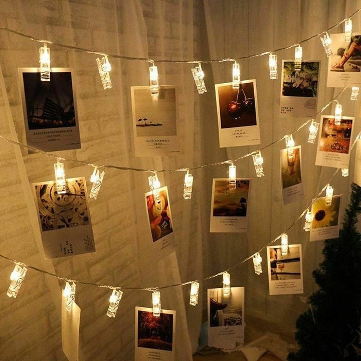 A string of glowing clothes pins with small instant photographs hanging from them