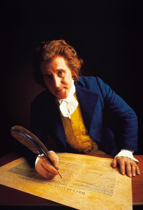 Jefferson sitting at a desk and writing the declaration with a quill