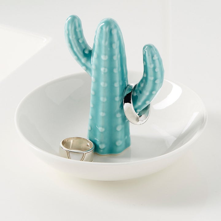 A ring holder with a small ceramic cactus in the middle