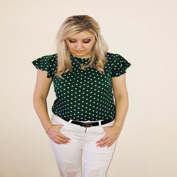 A reviewer wearing the short flutter sleeve, high-neck top in green and white polka dots