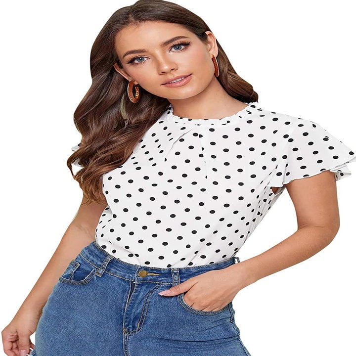 A model wearing the top in white with black polka dots