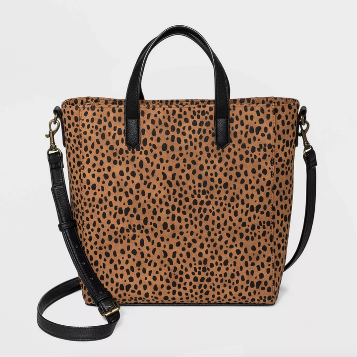 a tan and black cheetah spotted hand bag with a black handle and long black strap