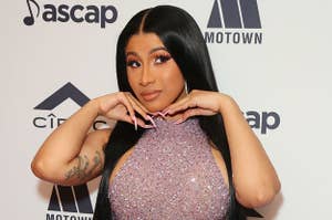 Cardi B wearing a halter dress with her hands under her chin