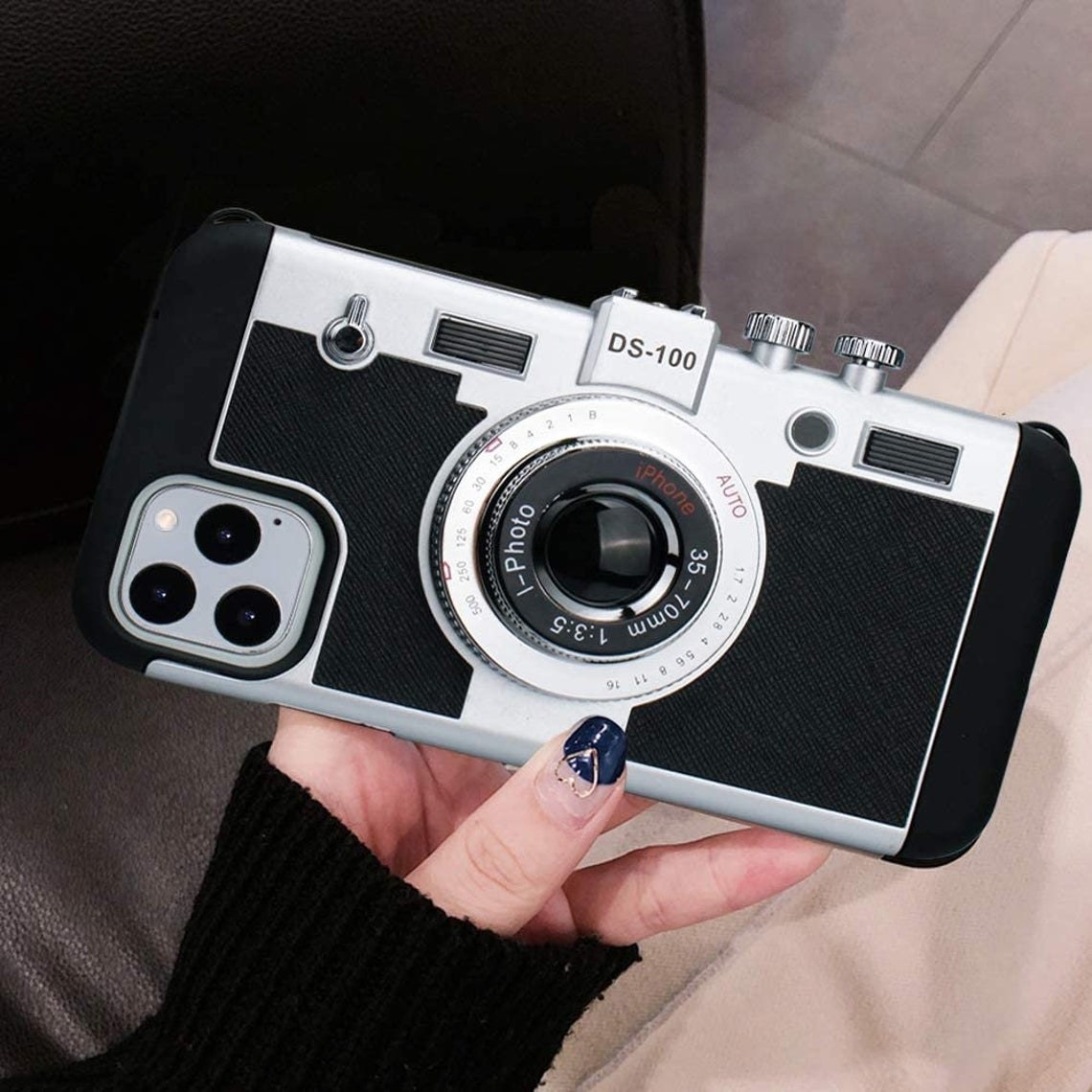 An iPhone case designed to look like a vintage camera with a camera lens and buttons