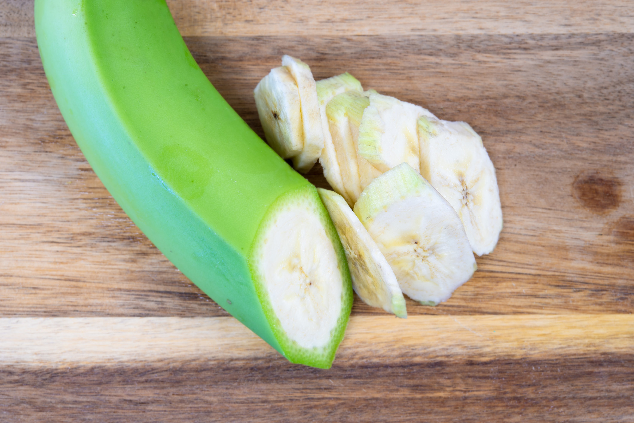 An unripe banana cut into thing slices