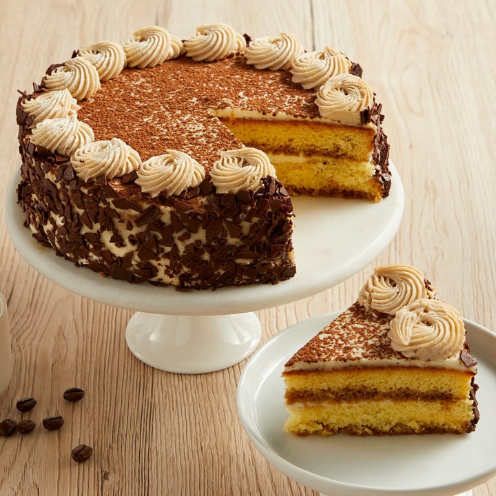 the multi-layered tiramisu cake with chocolate bits on the side and cocoa powder on top