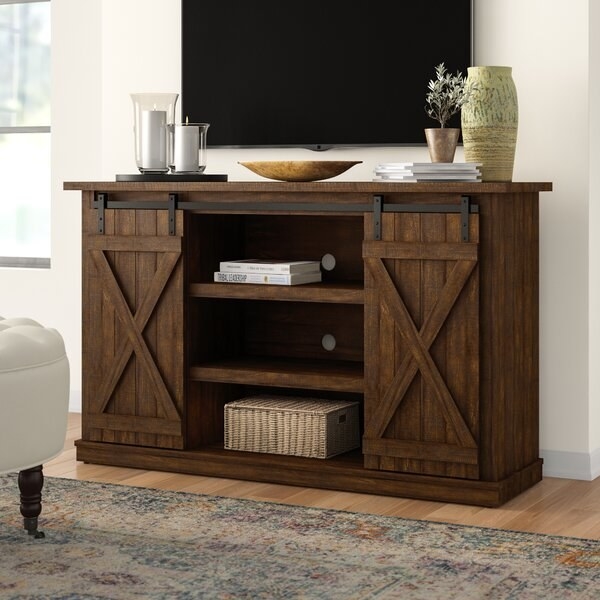 The console in brown, with an open middle area and sliding barn doors on either side which can move to reveal more shelving