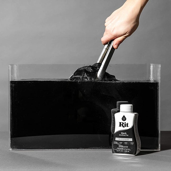 A hand dipping clothing in a tub of the dye and water