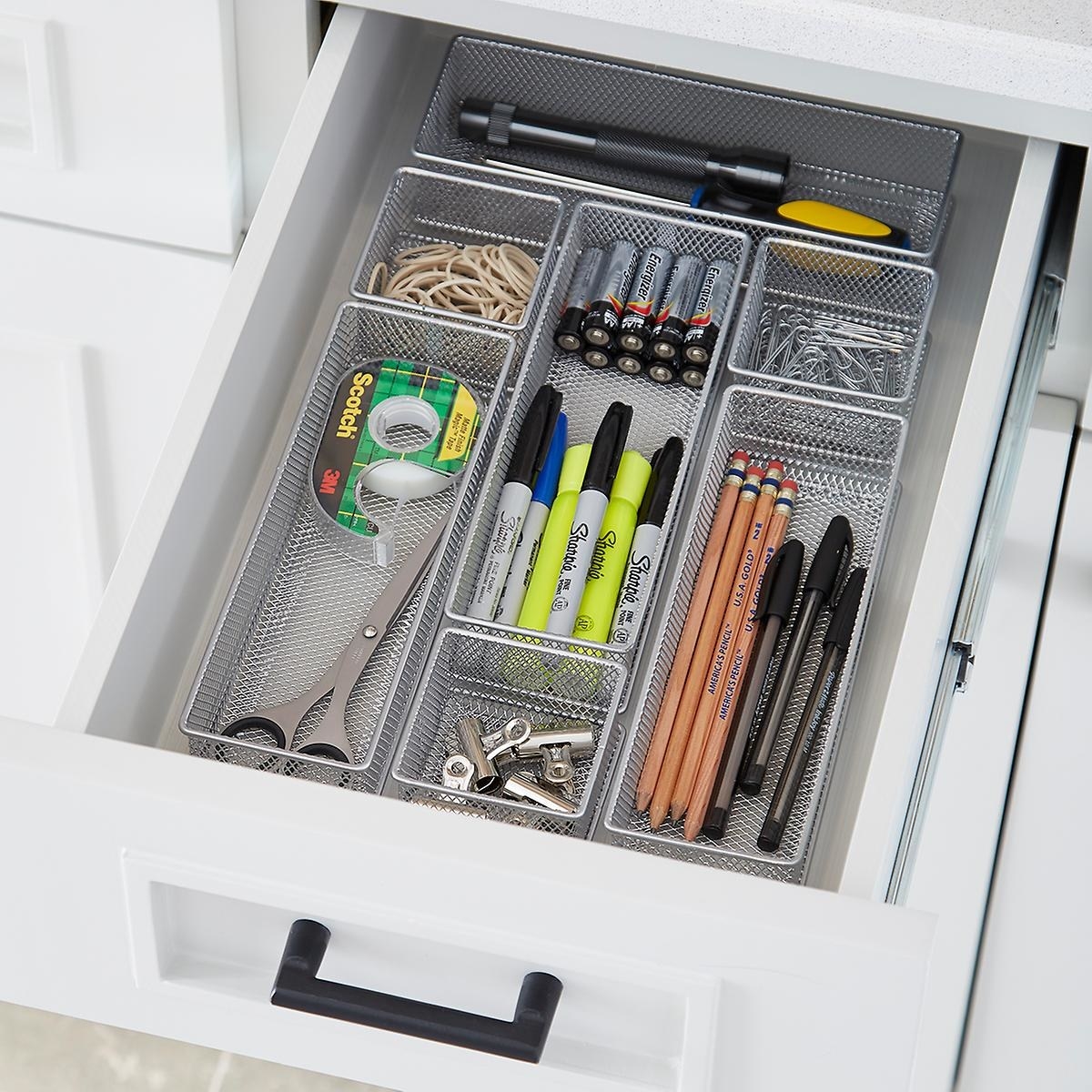The drawer organizer with individual compartments full of pens, pencils, and other office supplies