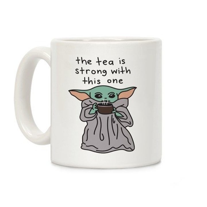 a mug with an illustration of baby yoda on it drinking tea