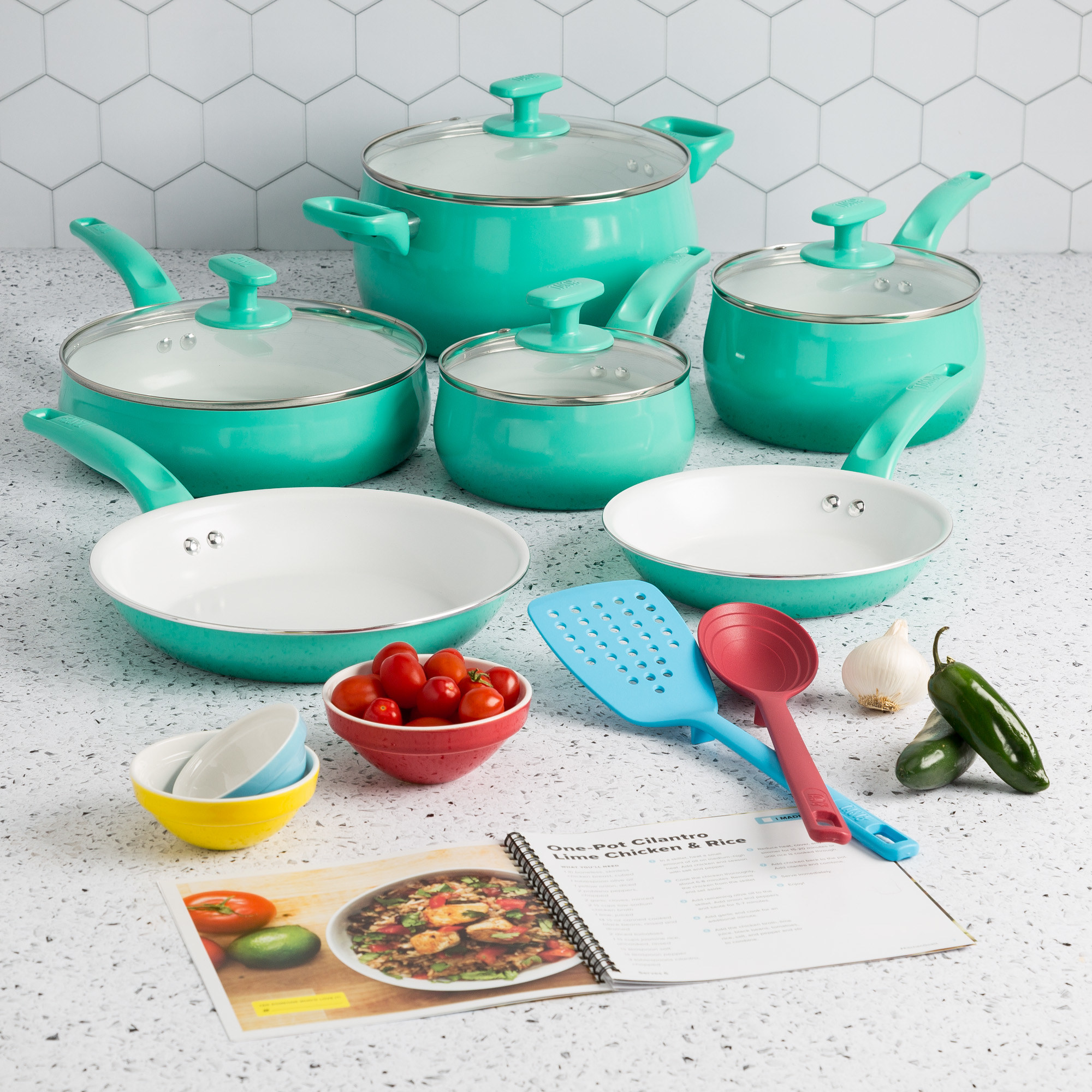 The green cookware set on a counter with recipe book