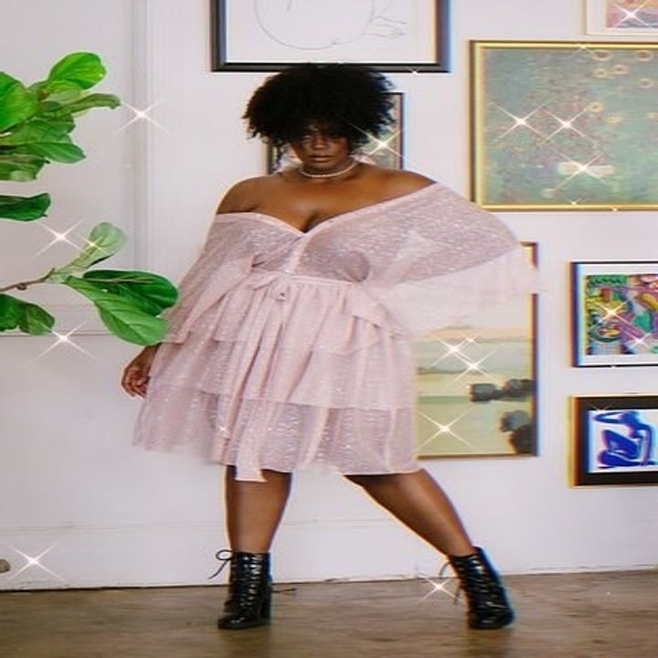 model wears pink mini dress with sleeves hanging off the shoulder