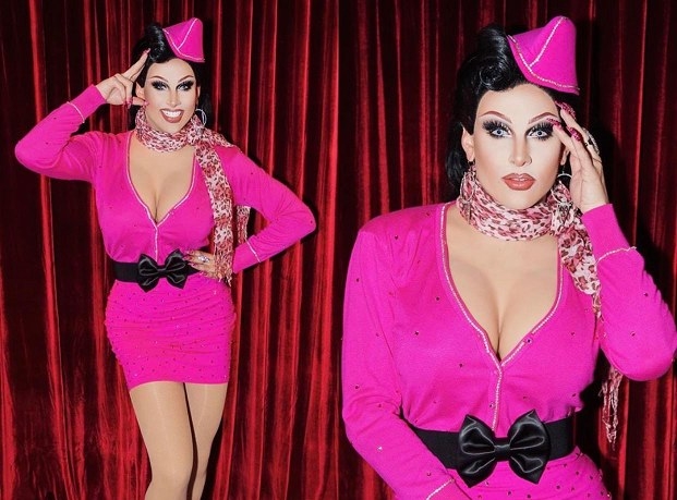 Drag queen Jan dressed as Michelle Visage in a low cut pink flight attendant outfit
