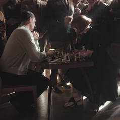 Beth playing a game of chess during a tournament; a crowd of people are watching
