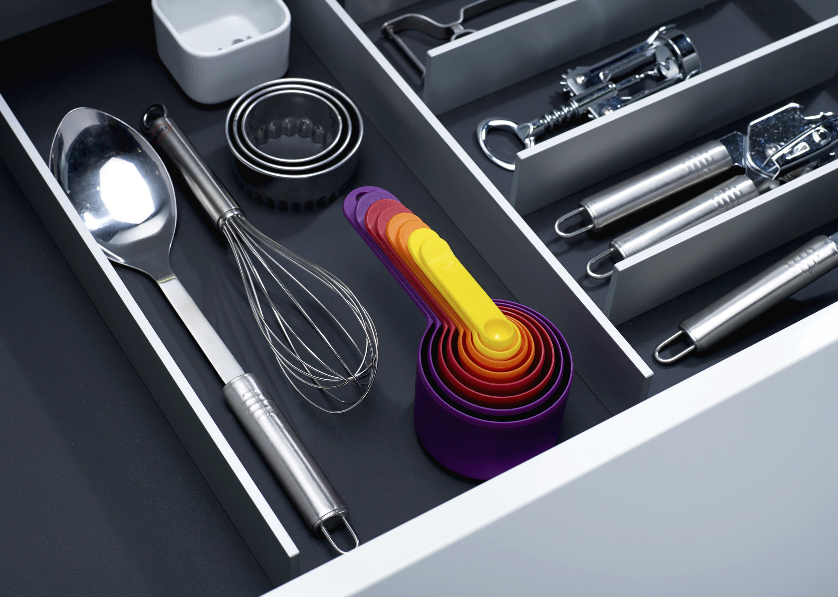The colorful cup set in a drawer with cutlery