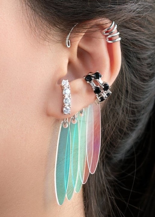 A set of three earring cuffs featuring jewels and colorful dangly parts designed like Harley Quinn's earrings from Birds of Prey