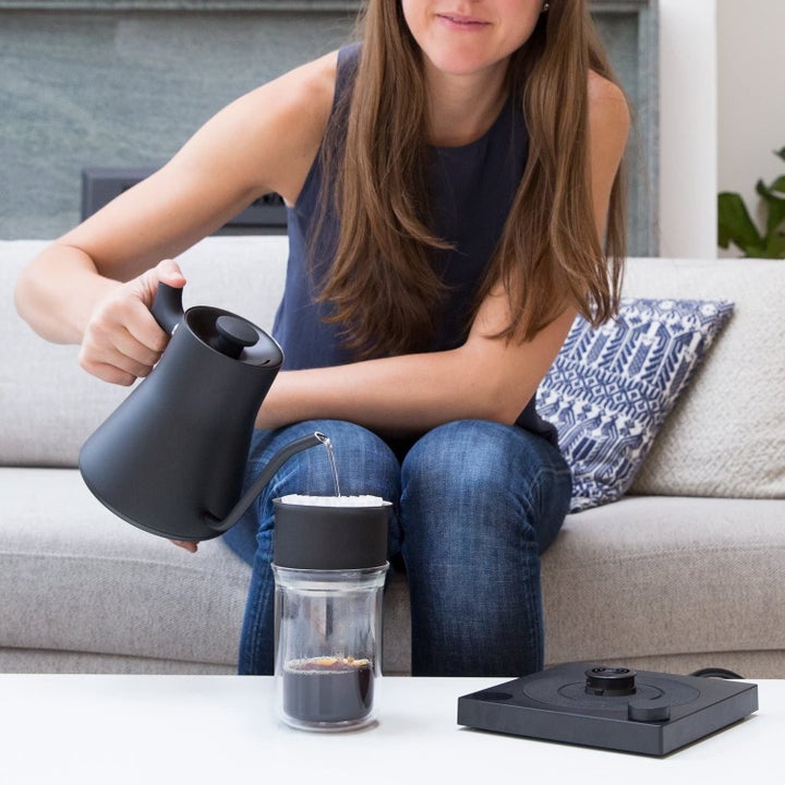 Model pouring water from kettle into coffee tumbler