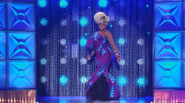 Drag queen Monet X Change wearing a purple gown with blue palm pattern and blonde dreadlock updo wig