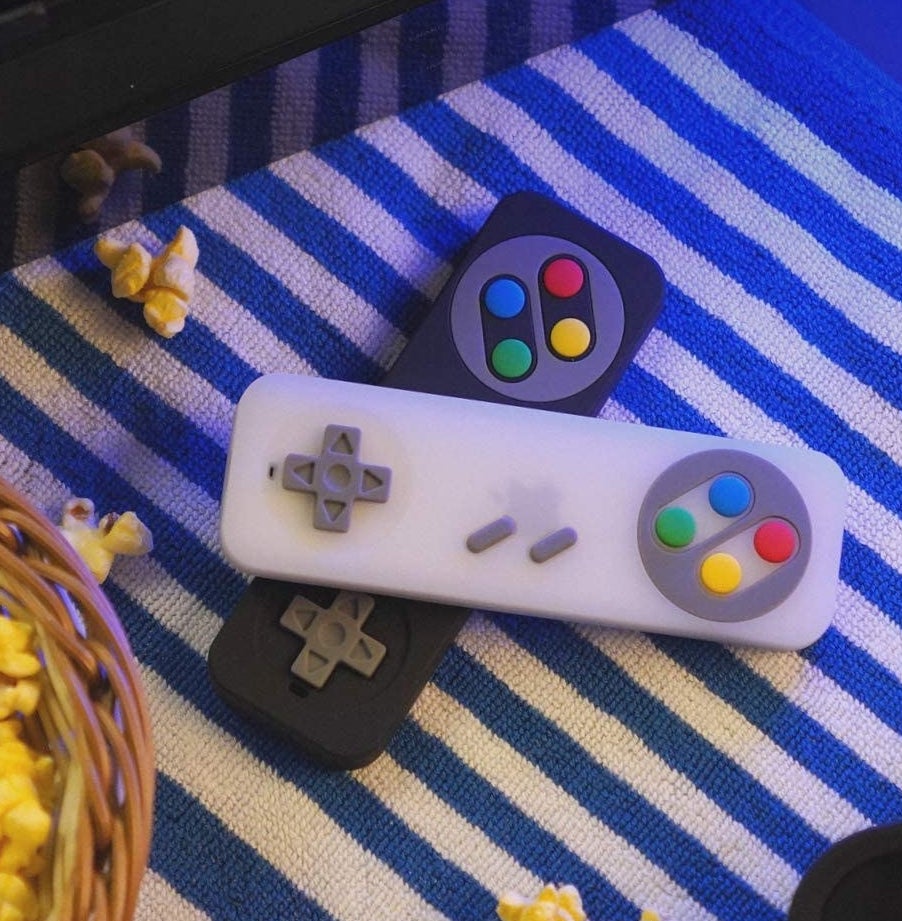 Two remotes stacked on top of each other next to a bowl of popcorn