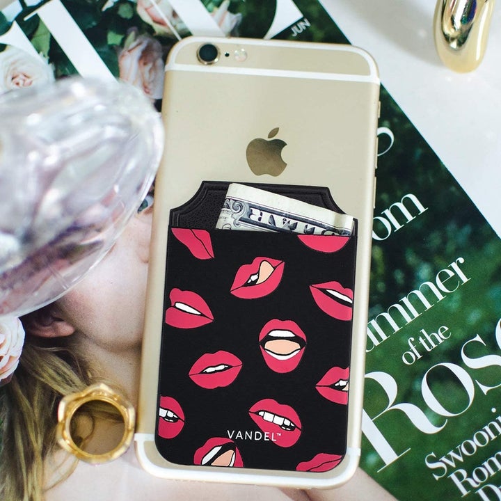 The black and red lip print pocket on an iPhone, holding a dollar bill
