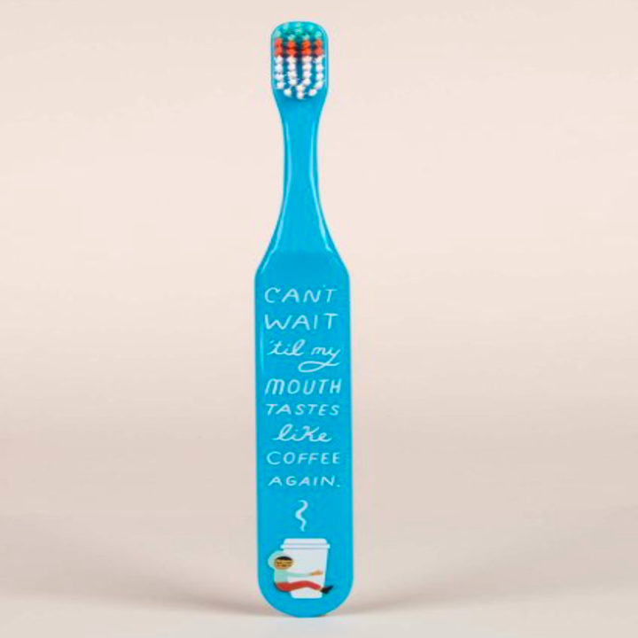 Blue toothbrush with the text "Can't wait 'til my mouth tastes like coffee again" and an illustrated coffee cup on the handle