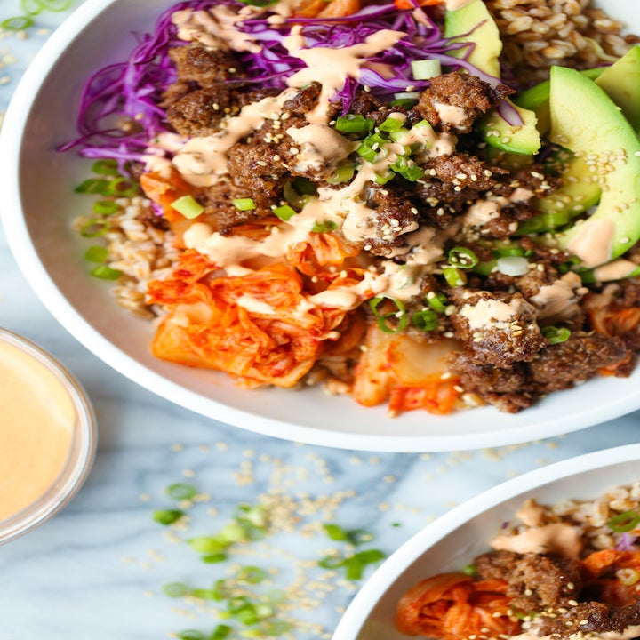 A close-up of a Korean beef bowl with cabbage, carrots, and avocado.