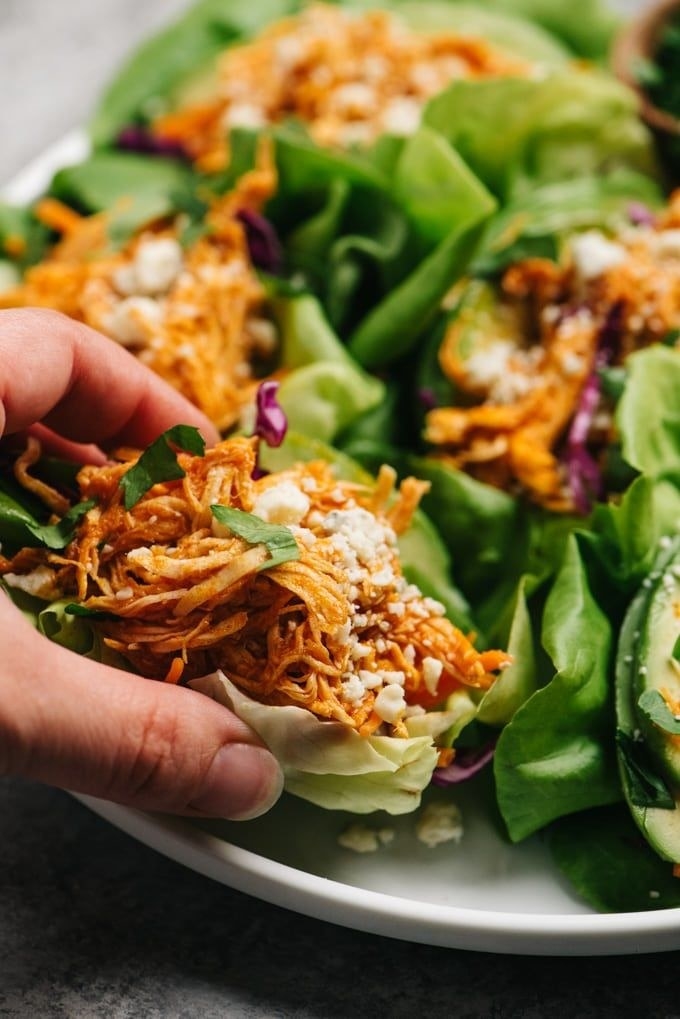 A hand holding a lettuce wrap stuffed with buffalo chicken.