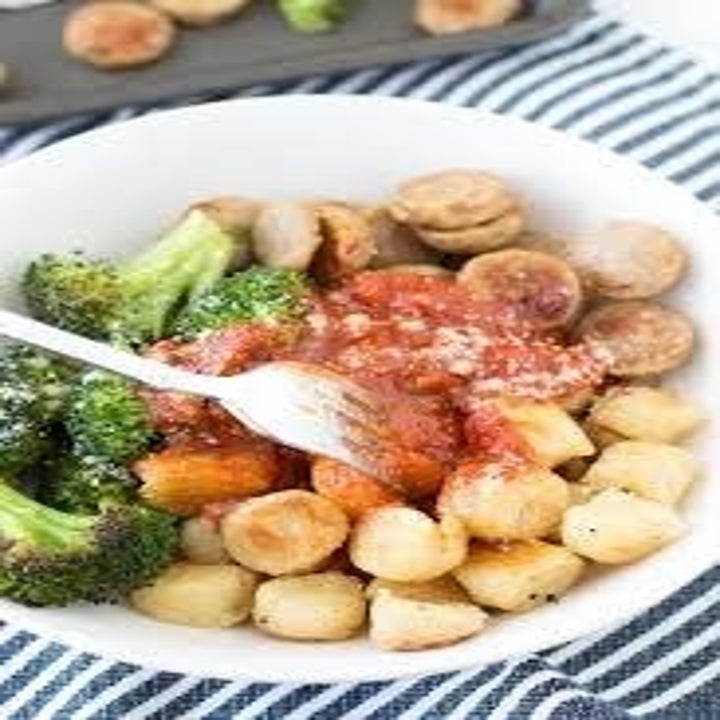 A bowl of cauliflower gnocchi, chicken sausage, and broccoli in tomato sauce.