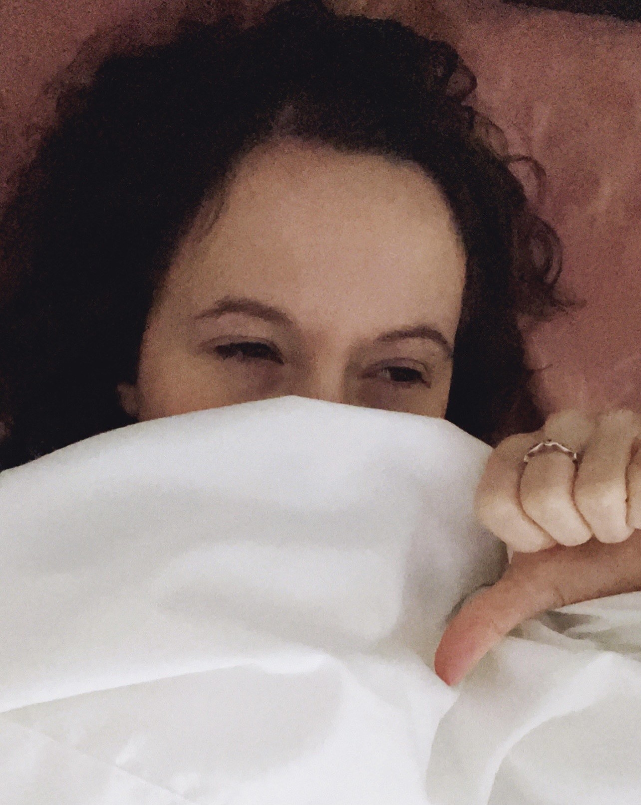 Person in bed with a thumbs-down