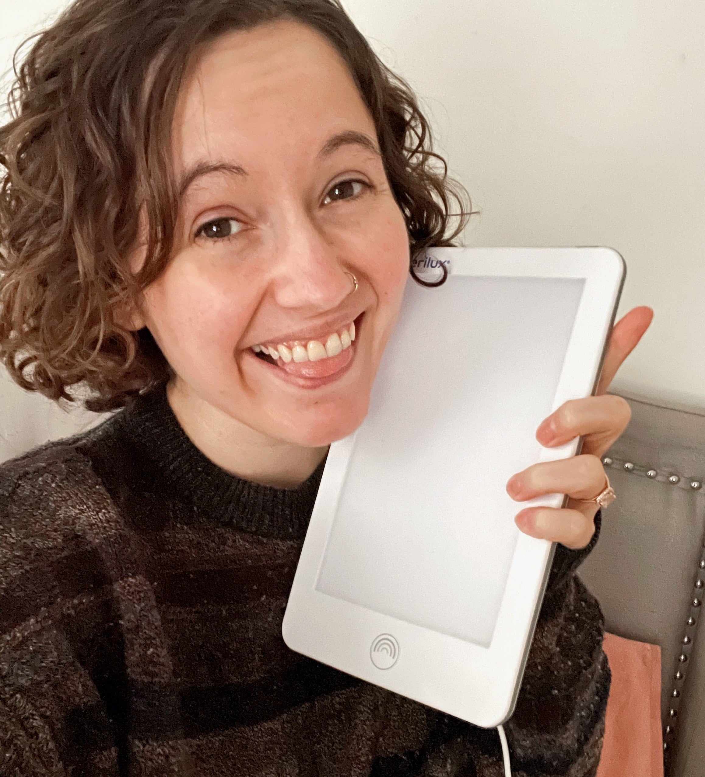 Person holding a light therapy lamp and smiling