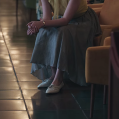 A closeup of Beth's full-length skirt, which is grey, and her matching shoes