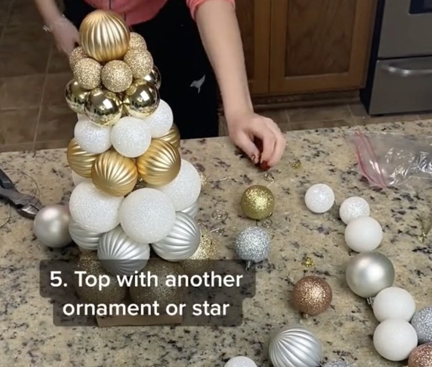 A woman crafting a small tree made of a pile of ornaments