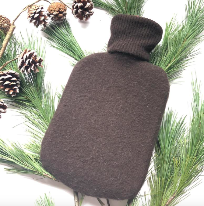 An upcycled cashmere hot water bottle cozy on a bed of fir branches
