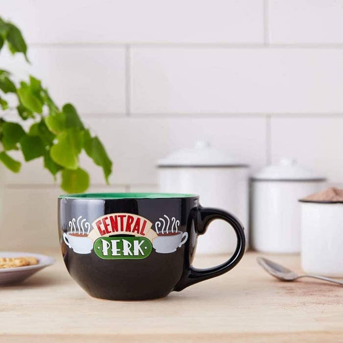 central perk mug on a kitchen table surrounded by jars and a spoon