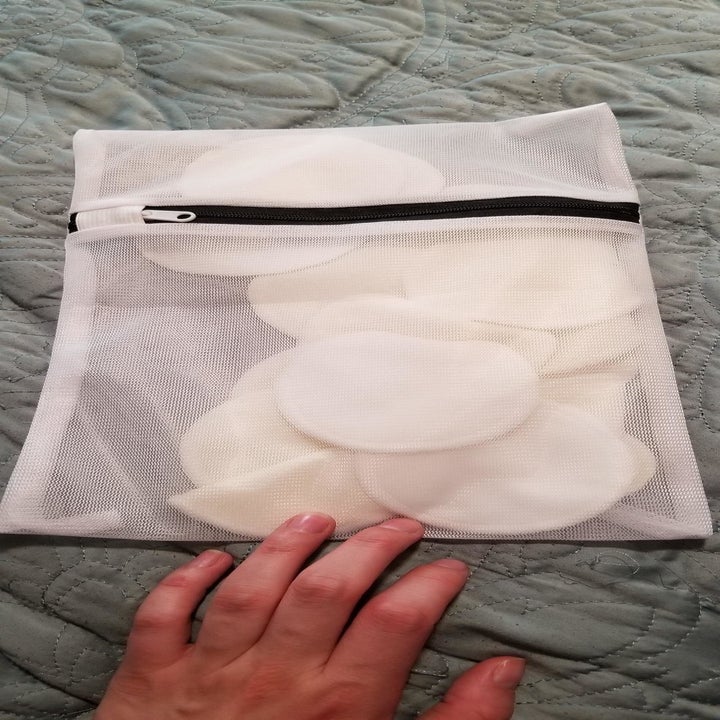 A reviewer holding the mesh bag of face pads