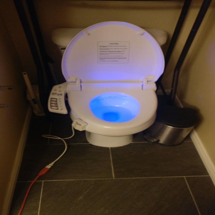 a reviewers toilet seat glowing blue inside and the bidet attached