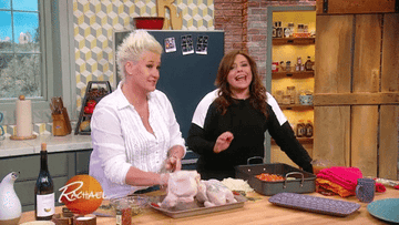 Anne Burrell playfully shakes a whole, raw, plucked chicken on the Rachel Ray talk show
