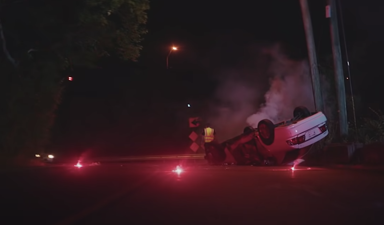 A car is turned over on the street with accident flares around it