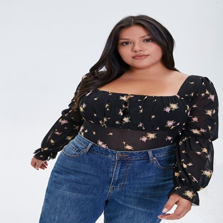 a model in a black floral body suit with puffy sleeves