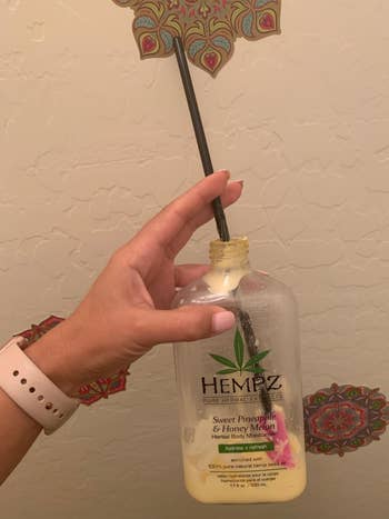 A reviewer using the larger spatula with a bottle of lotion
