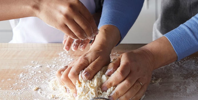 models' hands kneading dough