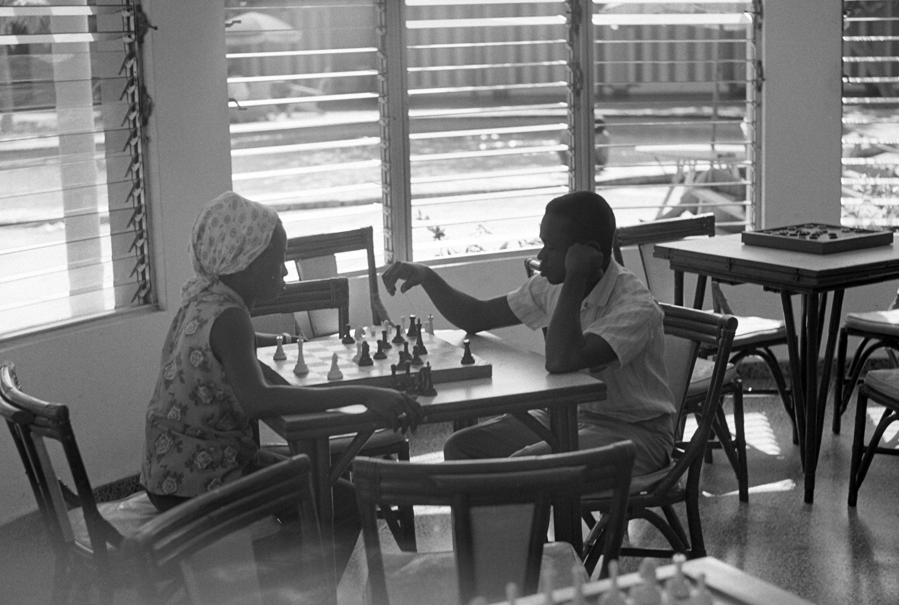 A man and woman play chess in a hotel lobby