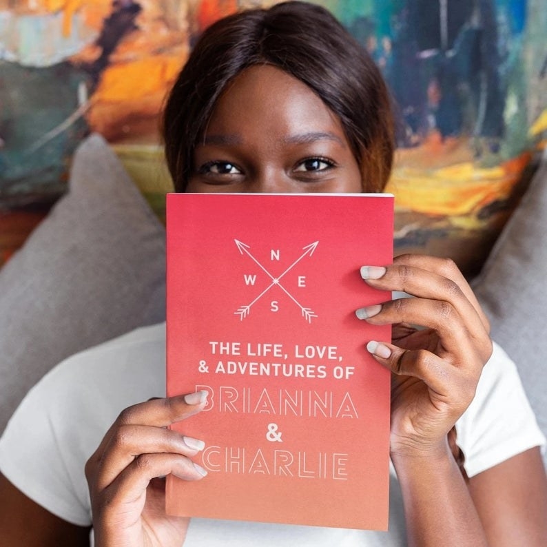 A person holding the book, which says &quot;The Life, Love, &amp;amp; Adventures OF Brianna &amp;amp; Charlie&quot;