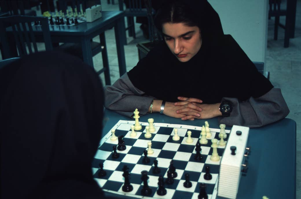 Two women with head coverings playing chess