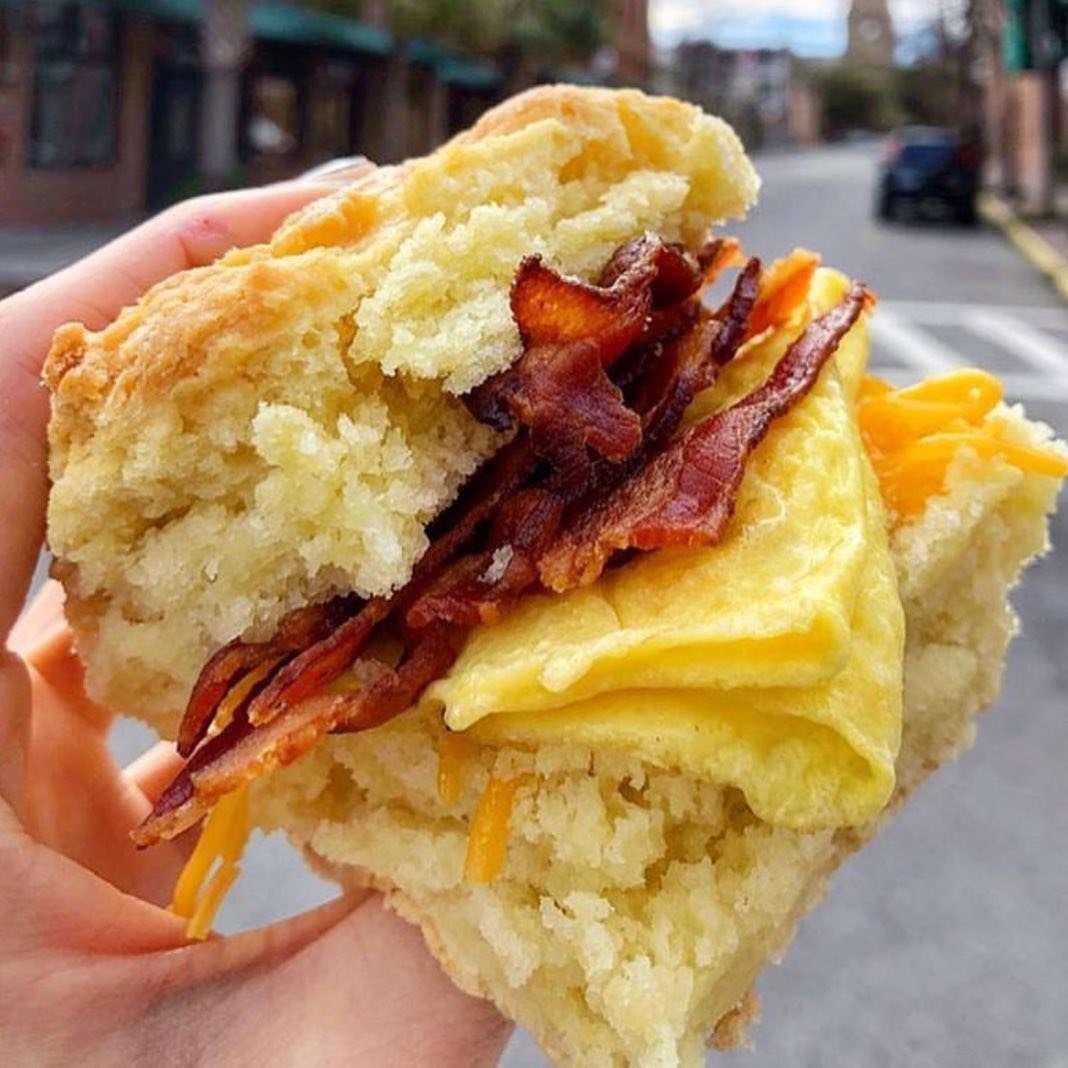 hand holding biscuit with bacon and eggs inside