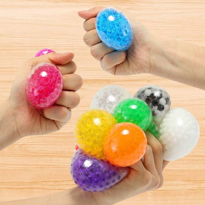 three hands squeezing water bead stress balls